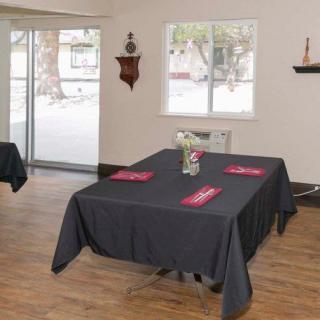 A simple dining room setup with black tablecloths and red napkins on tables.