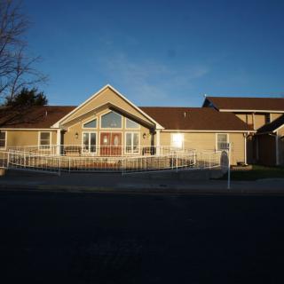 A suburban house with a fenced front yard, illuminated by the setting sun.
