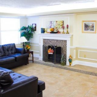 A cozy living room with a fireplace, two dark sofas, and decorative artwork on the walls.