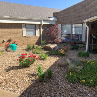 A serene courtyard garden featuring vibrant flowers and lush greenery.