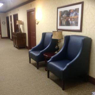 A hallway with blue chairs and a painting on the wall.