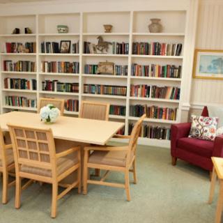A cozy reading corner featuring a table and chairs, surrounded by shelves filled with books.