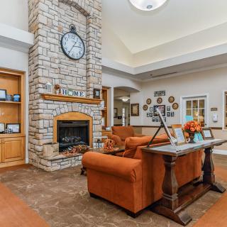 A cozy living room with a stone fireplace, central clock, and comfortable seating.