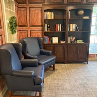 A cozy corner with blue armchairs and a wooden bookshelf in a warmly decorated room.