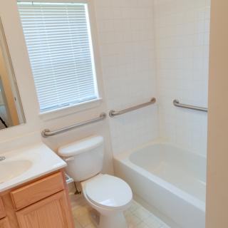 A clean and simple bathroom with a bathtub, toilet, and vanity.