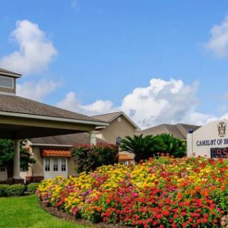 A building surrounded by vibrant flowers and a sign under a clear blue sky.