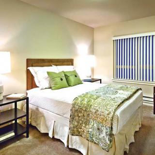 A modern bedroom with a neatly made bed, decorative pillows, and stylish nightstands.