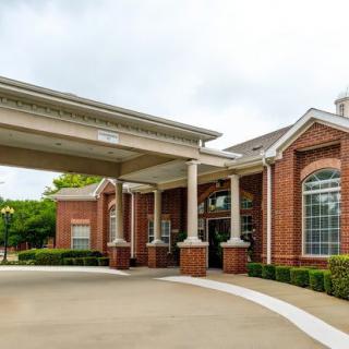 A brick building with a covered entrance and large windows.
