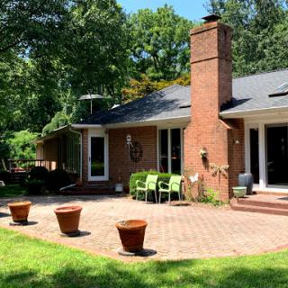 A charming brick house surrounded by lush greenery and a cozy outdoor seating area.