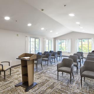 A well-lit conference room with arranged chairs and a podium.