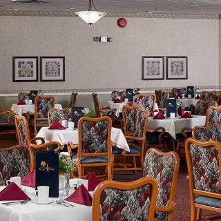A cozy dining room with elegantly set tables and patterned chairs.