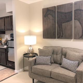 A cozy living room with a sofa, decorative artwork, and a view of the kitchen.