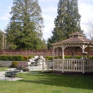 A serene garden featuring a gazebo, waterfall, and well-maintained landscaping.