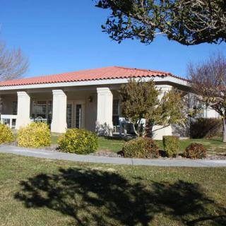 A modern house with a red-tiled roof surrounded by a garden on a sunny day.