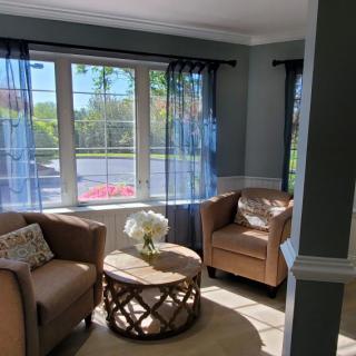 A cozy living room with two armchairs, a coffee table, and large windows letting in natural light.