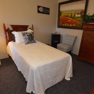 A cozy bedroom with a single bed, decorative pillows, and artwork on the wall.