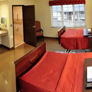 A well-furnished hotel room featuring two beds with red bedding and a cozy atmosphere.
