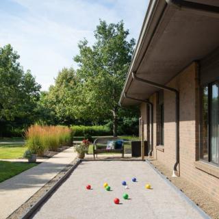 A sunny garden with a bocce court next to a modern house.