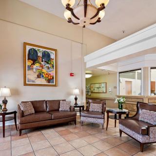 A hotel lobby featuring a comfortable seating area with sofas and chairs, elegant decor including a chandelier and artwork on the wall.