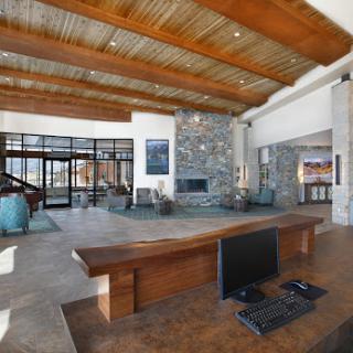 A spacious and modern lobby featuring wooden beams, a stone wall with a fireplace, and an inviting workspace.