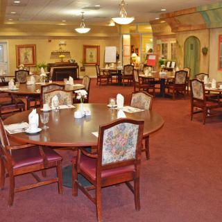 Spacious dining area with elegantly arranged tables and chairs, featuring warm lighting and decor.