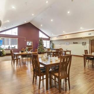 A spacious dining area with wooden tables and chairs, featuring a Christmas tree as decoration.