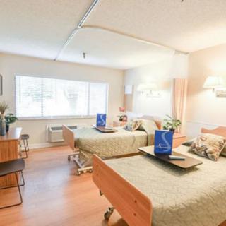 A bright hospital room with two beds and window light.