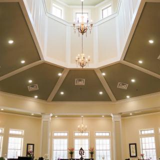 A beautifully designed interior featuring a dome ceiling with chandeliers and ample natural light from the windows.