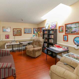 A cozy living room with comfortable seating, bookshelves, and various paintings on the walls.