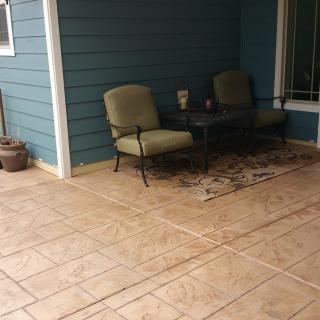 A cozy outdoor patio area with chairs, a table, and a decorative rug.