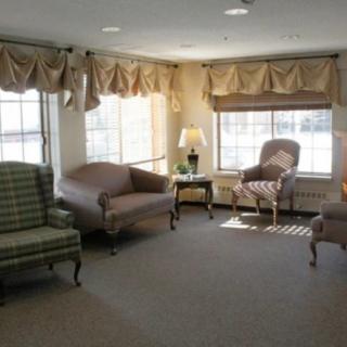 A cozy living room with sofas, chairs, and large windows.