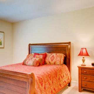 Cozy bedroom with wooden bed frame and vibrant bedding.