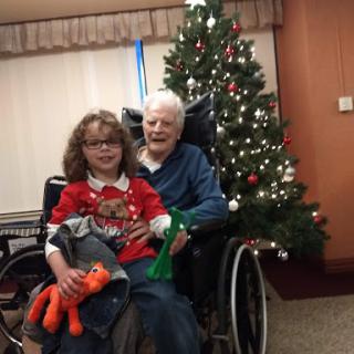 A joyful moment captured during the holiday season, featuring a child and an elderly person by the Christmas tree.
