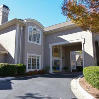 A two-story residential house with a driveway and surrounding greenery.
