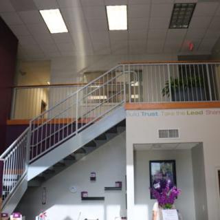 A modern office interior featuring a staircase and balcony with plants.