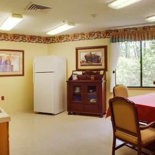 A cozy dining area with a refrigerator, a wooden cabinet, and a table set for meals.