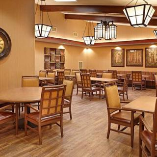 A cozy dining area with wooden tables and chairs, warmly lit by decorative light fixtures.