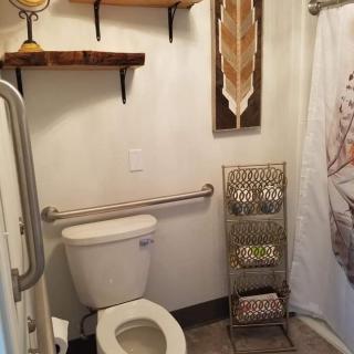 A compact bathroom with a toilet, shelves, a decorative shower curtain, and a towel rack.