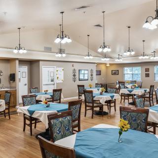A spacious dining room with neatly arranged tables and chairs, featuring elegant decor and warm lighting.