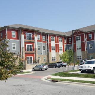 A modern apartment complex featuring a mix of brick and siding with adjacent parking spaces.