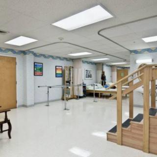 A spacious rehabilitation center room equipped with exercise stairs and parallel bars for physical therapy.