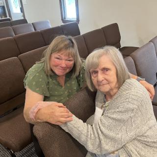 A moment of warmth and connection between two individuals, sharing smiles and companionship indoors.