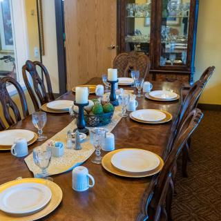 A well-set dining table with plates, cups, and candles in a cozy dining room.