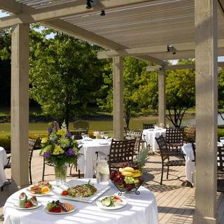 Elegant outdoor dining setup on a terrace with beautifully arranged tables, surrounded by lush greenery.