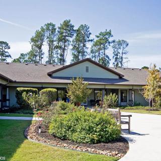 A scenic view of a single-story building surrounded by a landscaped garden and pathway.