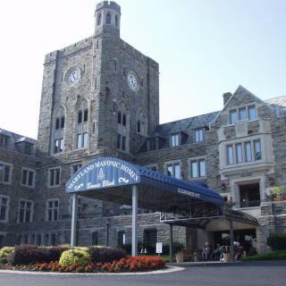 A stone building with a clock tower and a covered entrance.