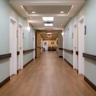 A well-lit hallway in a healthcare facility with multiple doors on either side.