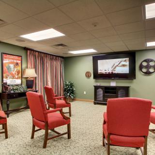 A cozy home theater setup with red chairs facing a large television in a warmly decorated room.