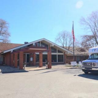 A brick building with a flagpole and a parked bus on a sunny day.