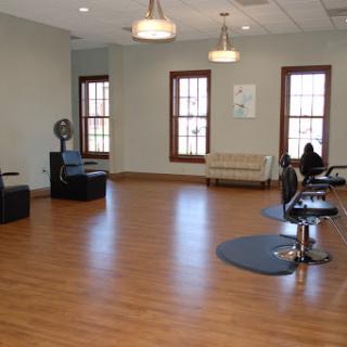 A spacious and modern hair salon featuring barber chairs and a cozy seating area.